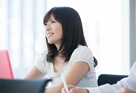 会議の席で、笑顔で話を聞く女性